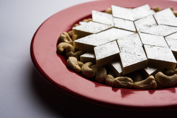 Kaju Katli is a Diamond shape Indian sweet made using cashew sugar and mava, served in a plate or bowl over moody background. selective focus