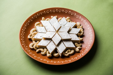 Kaju Katli is a Diamond shape Indian sweet made using cashew sugar and mava, served in a plate or bowl over moody background. selective focus
