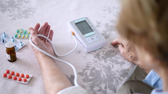 Elderly Woman Measuring Blood Pressure At Home