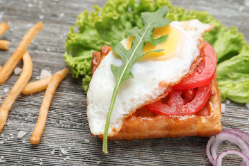 Delicious waffle with fried egg on wooden table