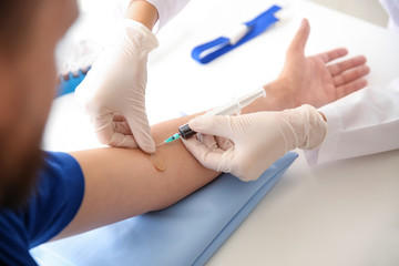 Female doctor drawing a blood sample of male patient in clinic