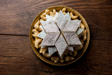 Kaju Katli is a Diamond shape Indian sweet made using cashew sugar and mava, served in a plate or bowl over moody background. selective focus