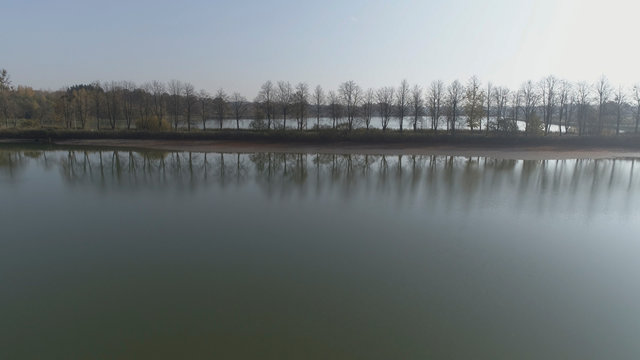 Aerial minimal style shot of misty autumn trees line in the background of the lake in Lithuania, Europe