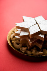 Kaju Katli is a Diamond shape Indian sweet made using cashew sugar and mava, served in a plate or bowl over moody background. selective focus