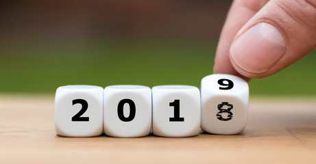 Hand is turning a dice and symbolically changes the year 2018 to 2019