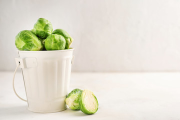 Bucket with fresh brussels sprouts on white table