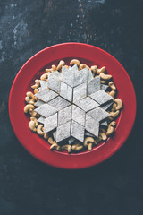 Kaju Katli is a Diamond shape Indian sweet made using cashew sugar and mava, served in a plate or bowl over moody background. selective focus