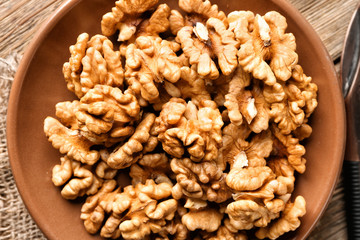 Plate with tasty walnuts on table, closeup