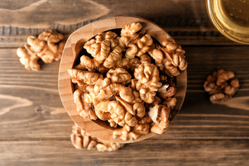 Bowl with tasty walnuts on wooden table