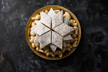 Kaju Katli is a Diamond shape Indian sweet made using cashew sugar and mava, served in a plate or bowl over moody background. selective focus