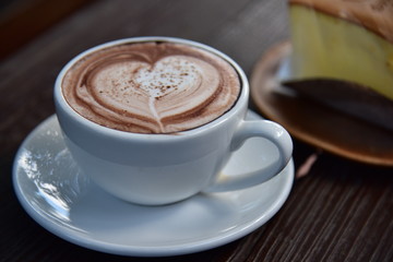 cup of coffee with cream on wooden background