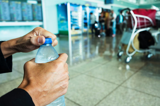 Man Opening A Water Bottle In A Station Or Airport.