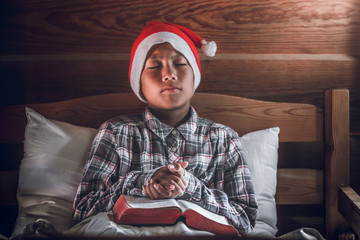 Boy reading and praying with holy bible on the wood bed at home.