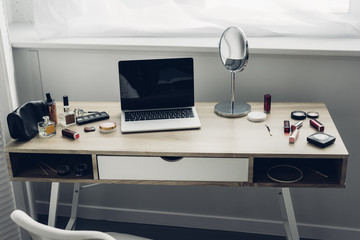 close-up shot of modern workplace with laptop and makeup supplies at home