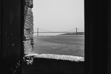Black and white view of 25 April Bridge from Belem Tower window in Lisbon, Portugal