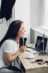 happy transgender man doing makeup at workplace at home