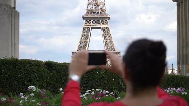 Woman taking picture of Eiffel Tower using smartphone in slow motion 180fps