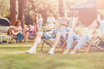 Young people relaxing on sunbeds in the park during summer