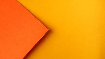 Orange paper on yellow papers.  Simple background. 