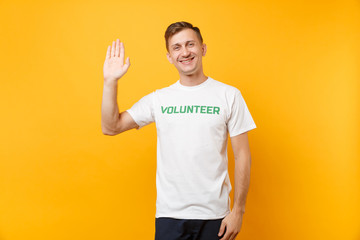 Portrait of happy smiling satisfied young man in white t-shirt with written inscription green title...