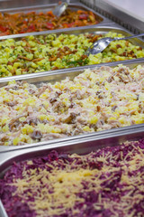 A variety of prepared salads on the counter in the supermarket