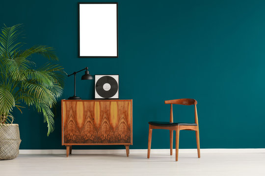 Mockup poster on pine green wall in scandinavian minimal interior with retro furniture and plant, real photo