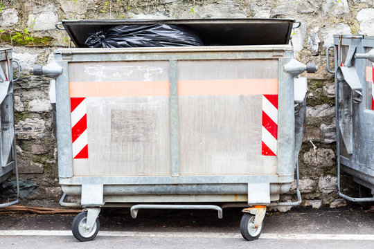 Dump garbage bin on street  near concret wall for waste