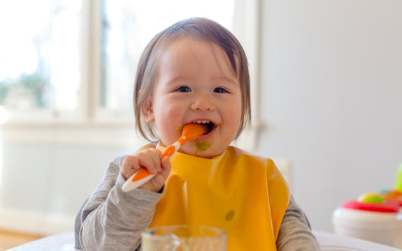Happy toddler boy smiling while eating a meal