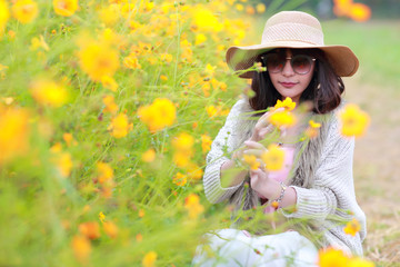 cute and beautiful girl with hat standing in nature outdoors among cosmos flowers field (rest time on vacation concept)