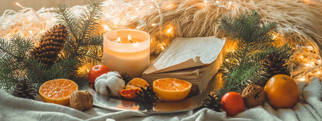 Book and Tangerines in a winter composition, Christmas trees, candles, cones, cotton, cinnamon....
