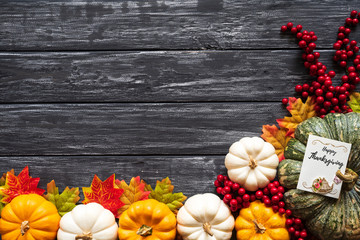 Top view of  Autumn maple leaves with Pumpkin and red berries on old wooden backgound. Thanksgiving...