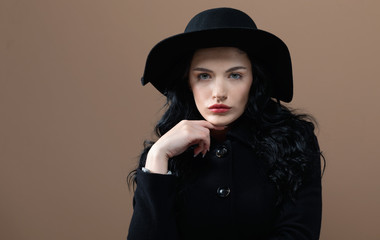 Beautiful young woman in a fashionable coat on a brown background