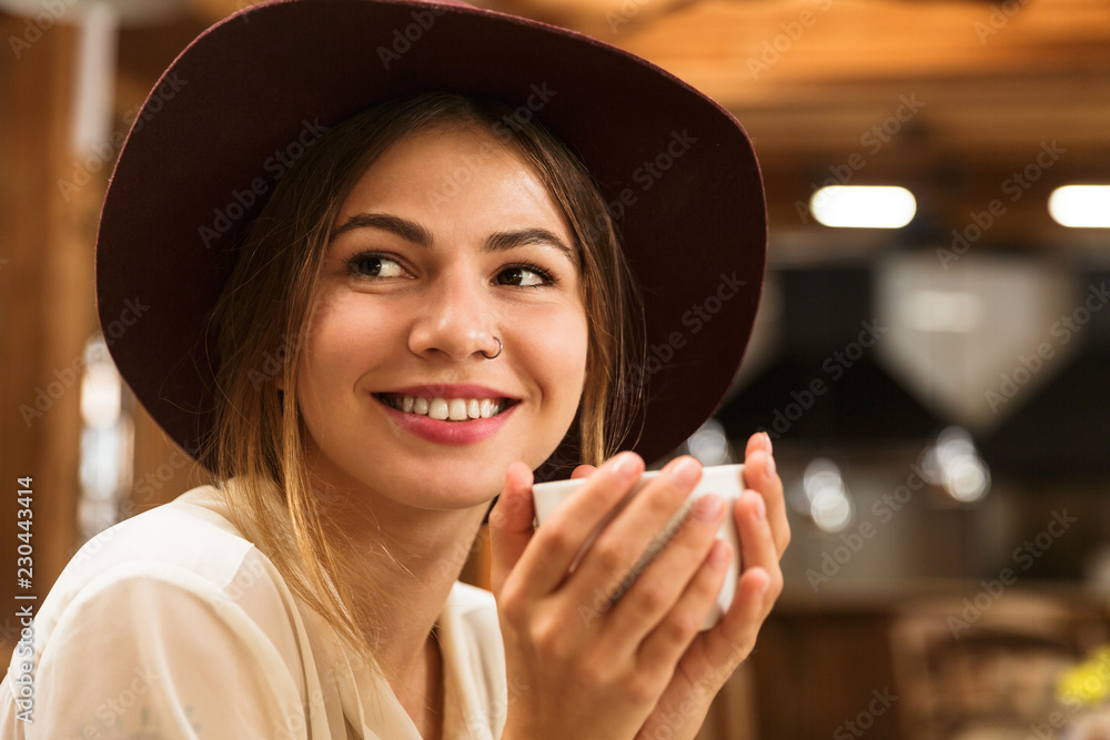 Sticker Close up of a happy girl in hat sitting at the cafe