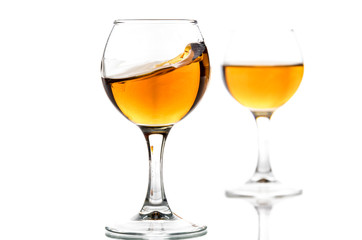A round glass with brandy and a splash of drink inside