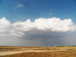 Landscape with windmills on the background of the sky and the field. Wind turbines farm. sandy beach. wind power. ecology