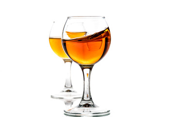 A round glass with brandy and a splash of drink inside