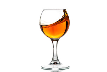 A round glass with brandy and a splash of drink inside