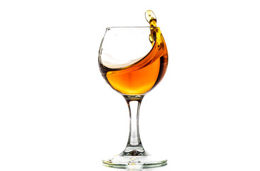 A round glass with brandy and a splash of drink inside