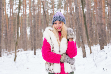 Fototapeta na wymiar Nature, fashion and people concept - Young attractive blond woman posing in the winter park.