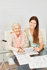Seniorin und Mädchen lösen zusammen Sudoku