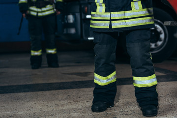 partial view of firefighters in protective fireproof uniform standing at fire station