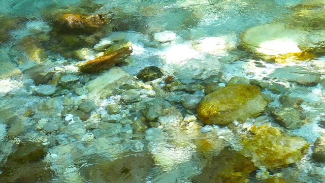 View of The River Soca as its crystal clear water flows in a rocky river bed in Slovenia.
