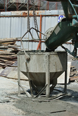 Concrete mixer lorry pouring wet concrete into concrete bucket at the construction site. 