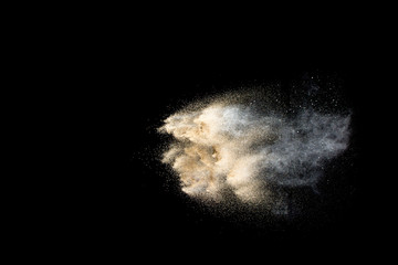 Dry river sand explosion. Golden colored sand splash against  black background.