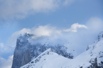 Fototapeta na wymiar Paysage en hiver à la montagne, campagne, avec la neige blanche qui recouvre la nature et des arbres sauf les sapins. Soleil qui perce entre les nuages au-dessus des vallées enneigées des Alpes