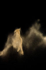 Dry river sand explosion. Golden colored sand splash against  black background.