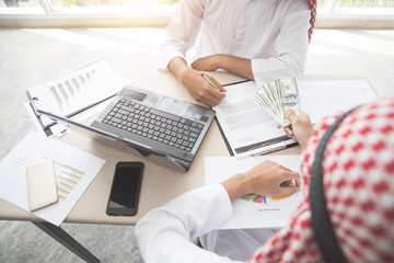 arab saudi businessman receive money after signing contract using as business background (concept of teamwork and partnership)