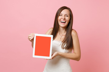 Portrait of laughing bride woman in wedding dress hold tablet pc computer with blank black empty screen isolated on pastel pink background. Wedding to do list. Organization of celebration. Copy space.