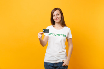 Portrait of young woman in white t-shirt with written inscription green title volunteer hold credit...