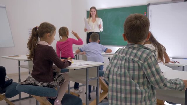 junior school, happy children get up from their desks and run up to the female teacher to hug her after lesson